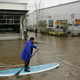 A man uses a paddle board to make his way through flooded streets in Sebastopol, California in February.